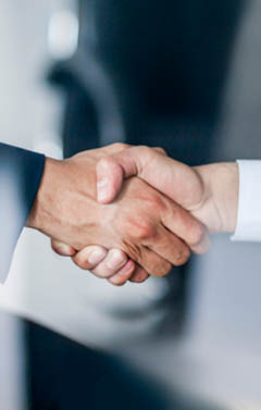 Business handshake in glass reflection in office